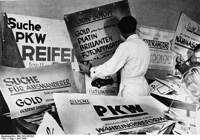 Werbegraphiker bei der Arbeit an neuen Plakaten. Die Wirtschaft Westdeutschlands richtet sich für den Tag der Währungsreform ein.