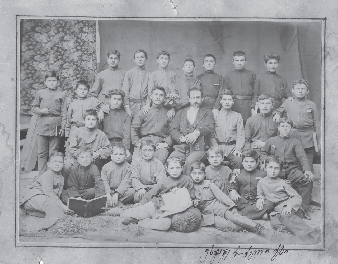 Schüler und Lehrer der Kirchenschule von Gori, Russisches Kaiserreich (1892). Iosseb Dschughaschwili befindet sich als Vierter von links in der oberen Reihe. Es handelt sich um die älteste öffentlich bekannte Fotografie von Stalin.